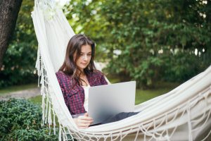 young woman lies hammock with laptop garden works remotely 2048x1367