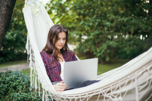 young woman lies hammock with laptop garden works remotely 300x200